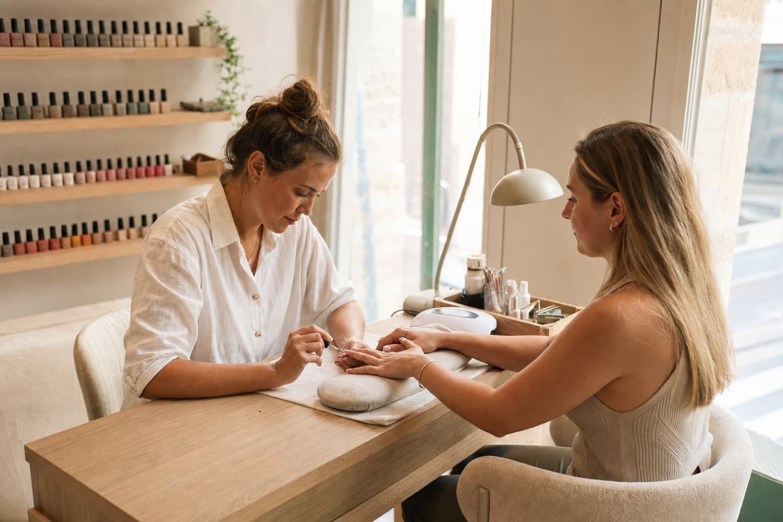 Prothésiste ongulaire appliquant du gel sur les ongles d'une cliente